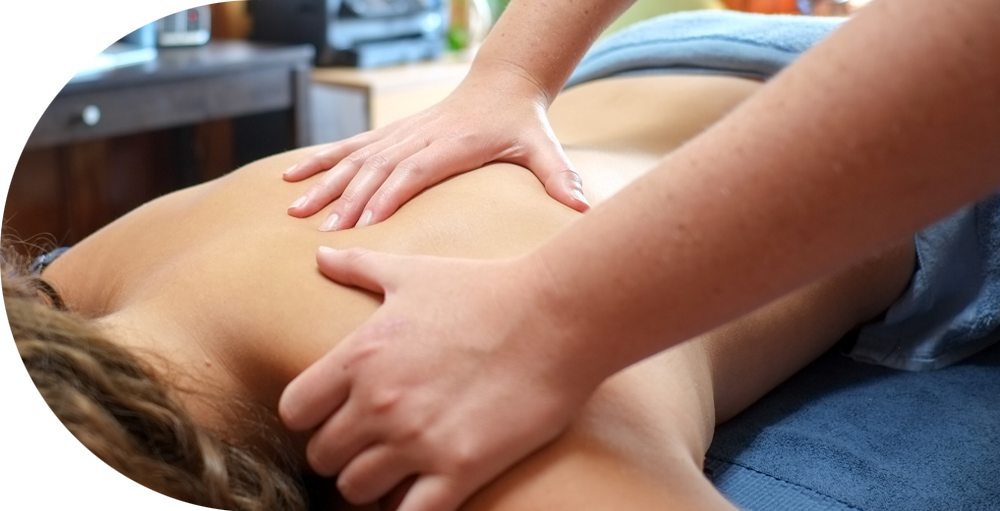 Hands massaging the back of a woman lying face down on treatment table.